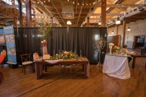 A table decorated with flower jar in front of black curtains