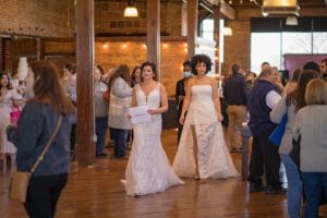 a group of women in white dresses walking down a wood floor