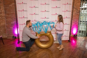 A Man on his knees with a ring shaped balloon