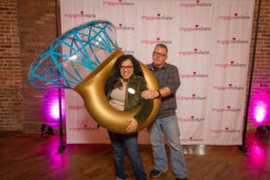 A Women Wearing a ring shape ballon and a man standing behind her