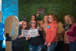 A Group of women are taking photo with the pamplet of Best Wedding Ever