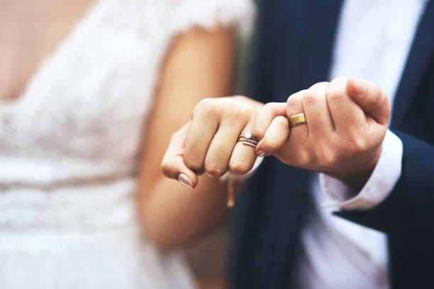 A close shot of a newly-wed couple posing with their wedding ring