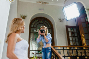 Young photographer is taking pictures the bride in the studio